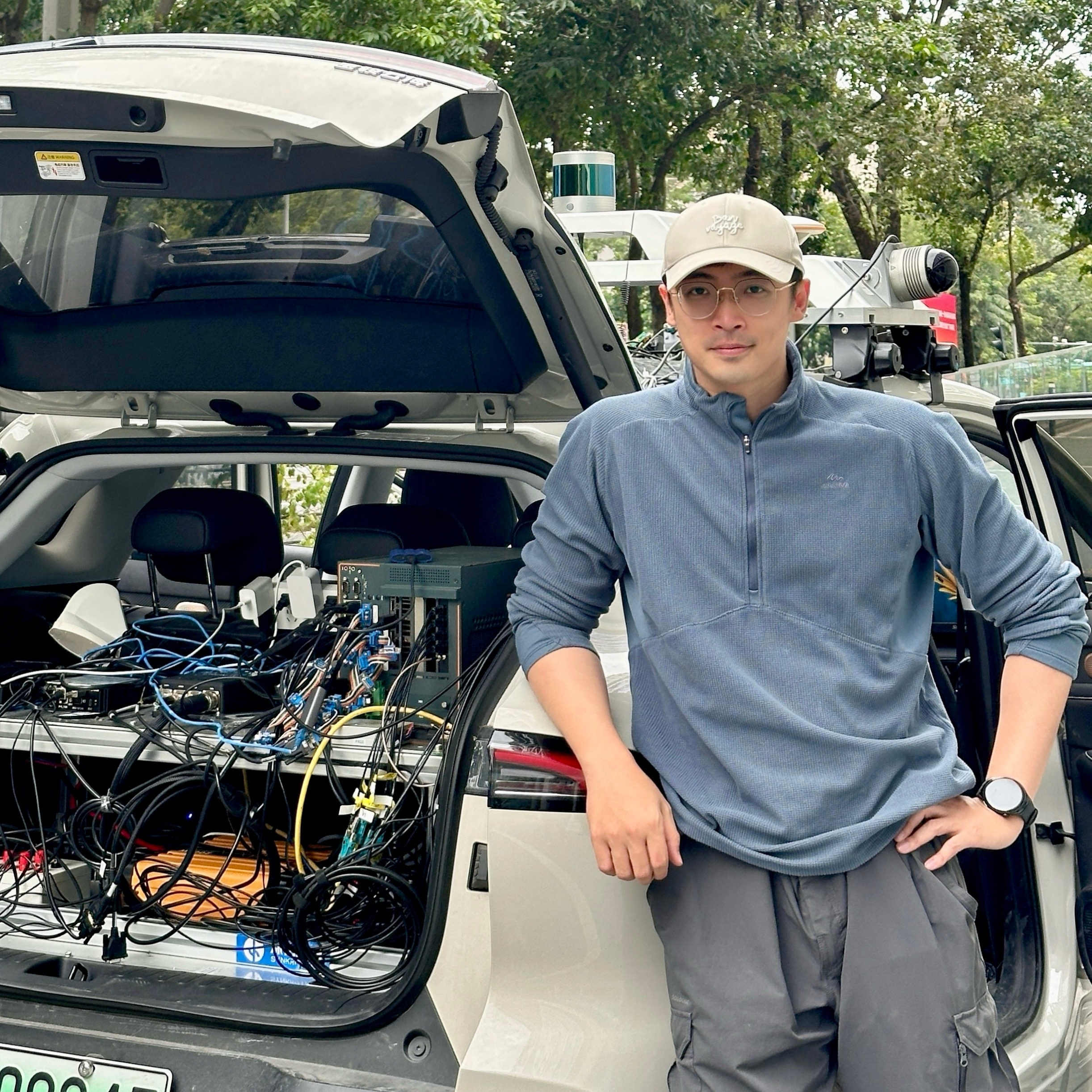 Jingcheng Wang beside an instrumented research vehicle